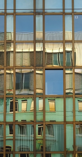 Façade d'immeuble en verre avec le reflet de maisons