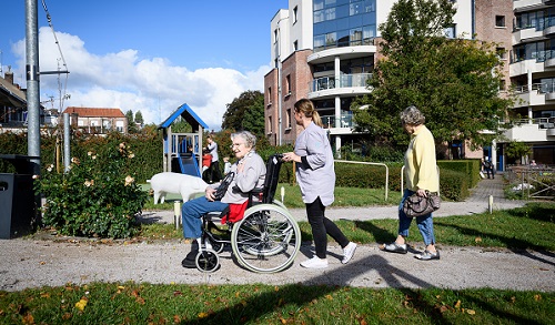 Personne âgée en fauteuil roulant promenée dans un parc