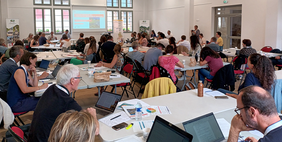 table ronde du séminaire (salle pleine avec gens réunis par petits groupes)