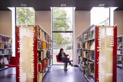 Femme assise au milieu de livres dans une bibliothèques