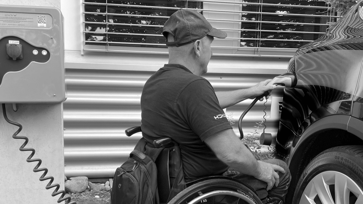 Usager en fauteuil roulant rechargeant un véhicule électrique